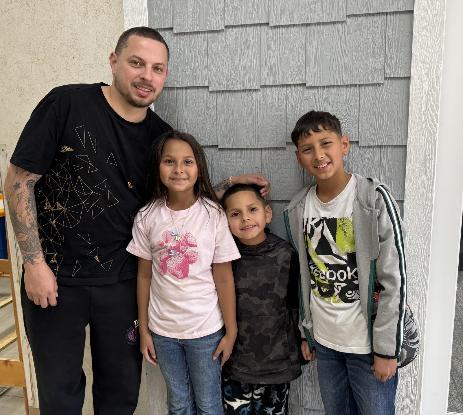 Family with father on the left followed by a young daughter and two young sons.