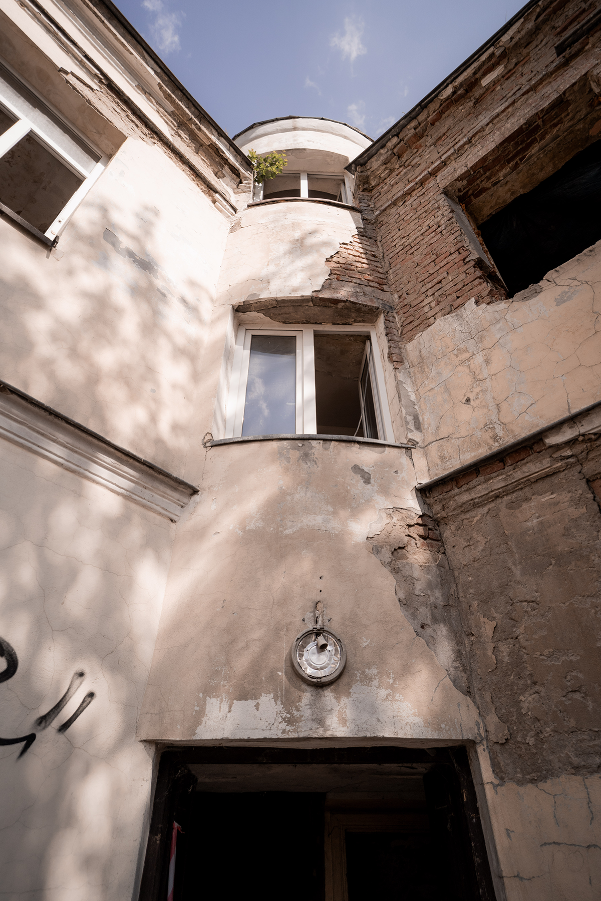 The front facade of the historic tenement being turned into apartments in Poland featuring stone-colored walls and white-framed windows. 