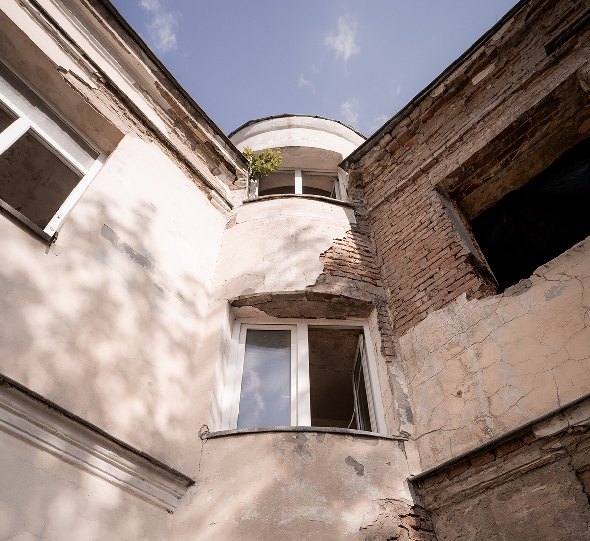 Vertical photo of an abandoned building that will become a part of Empty Spaces featuring stone colored walls and broken open windows.