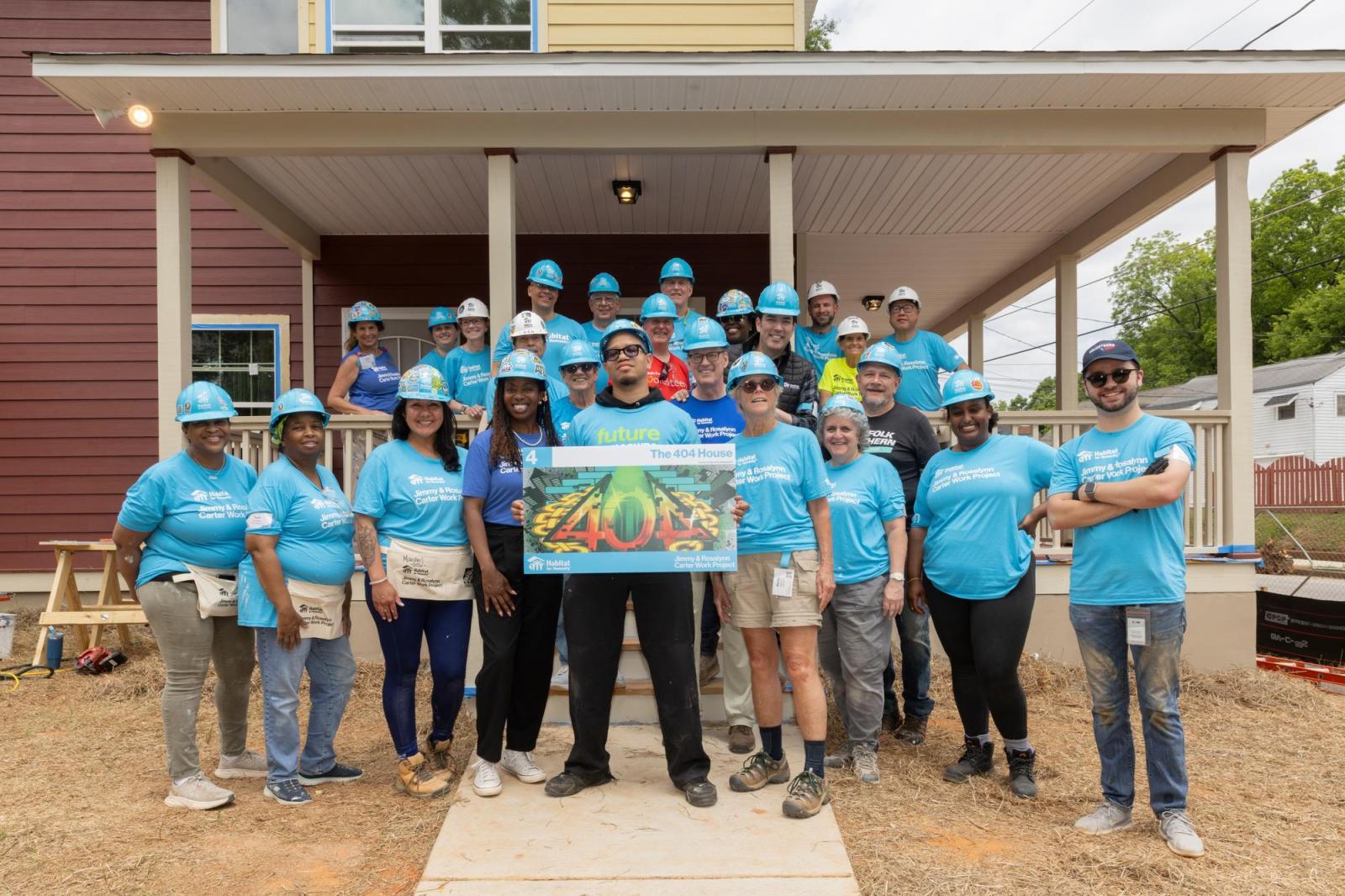 House 4 volunteers posing for group photo in front of house.