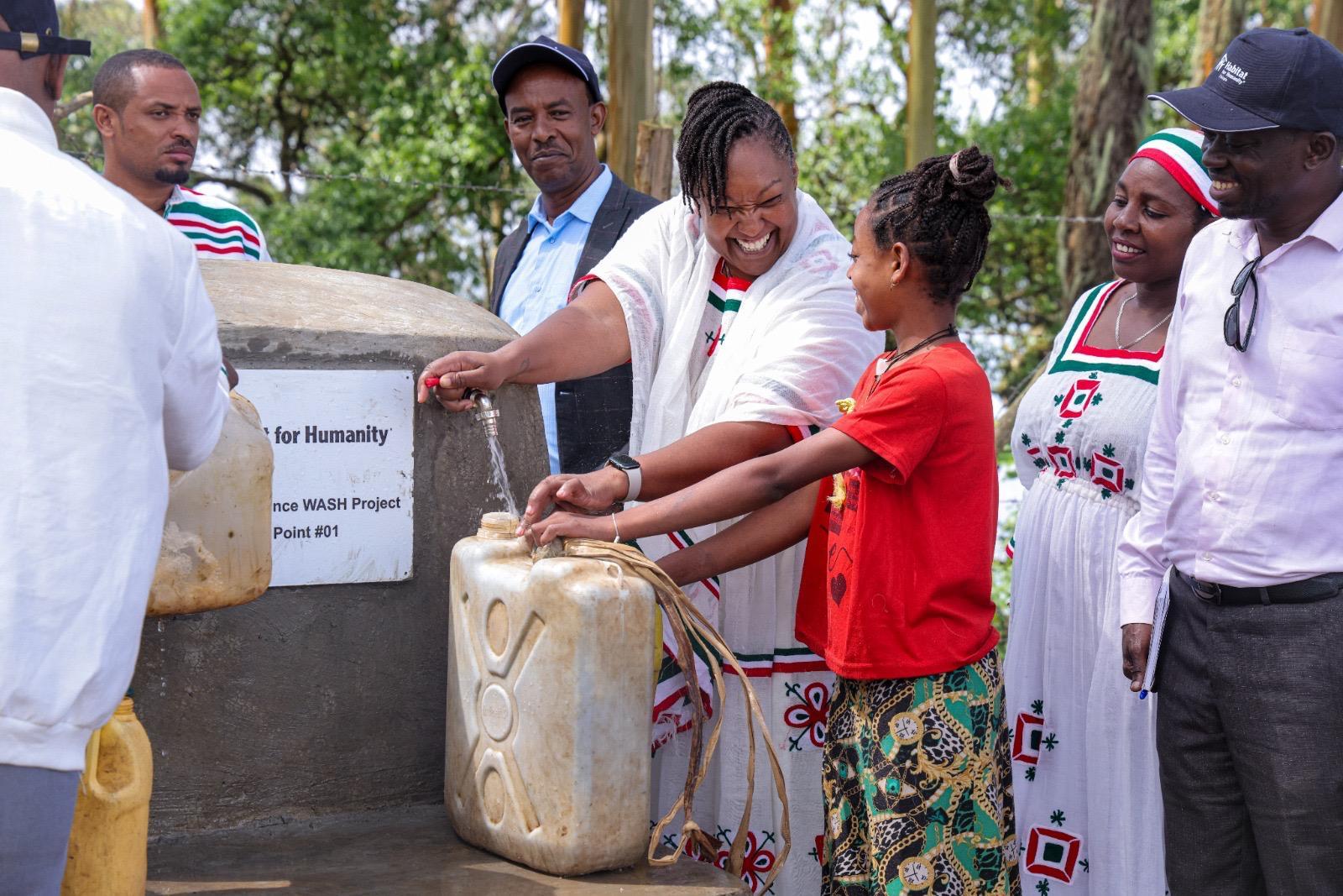 People standing at a water point fetching water at a ceremony