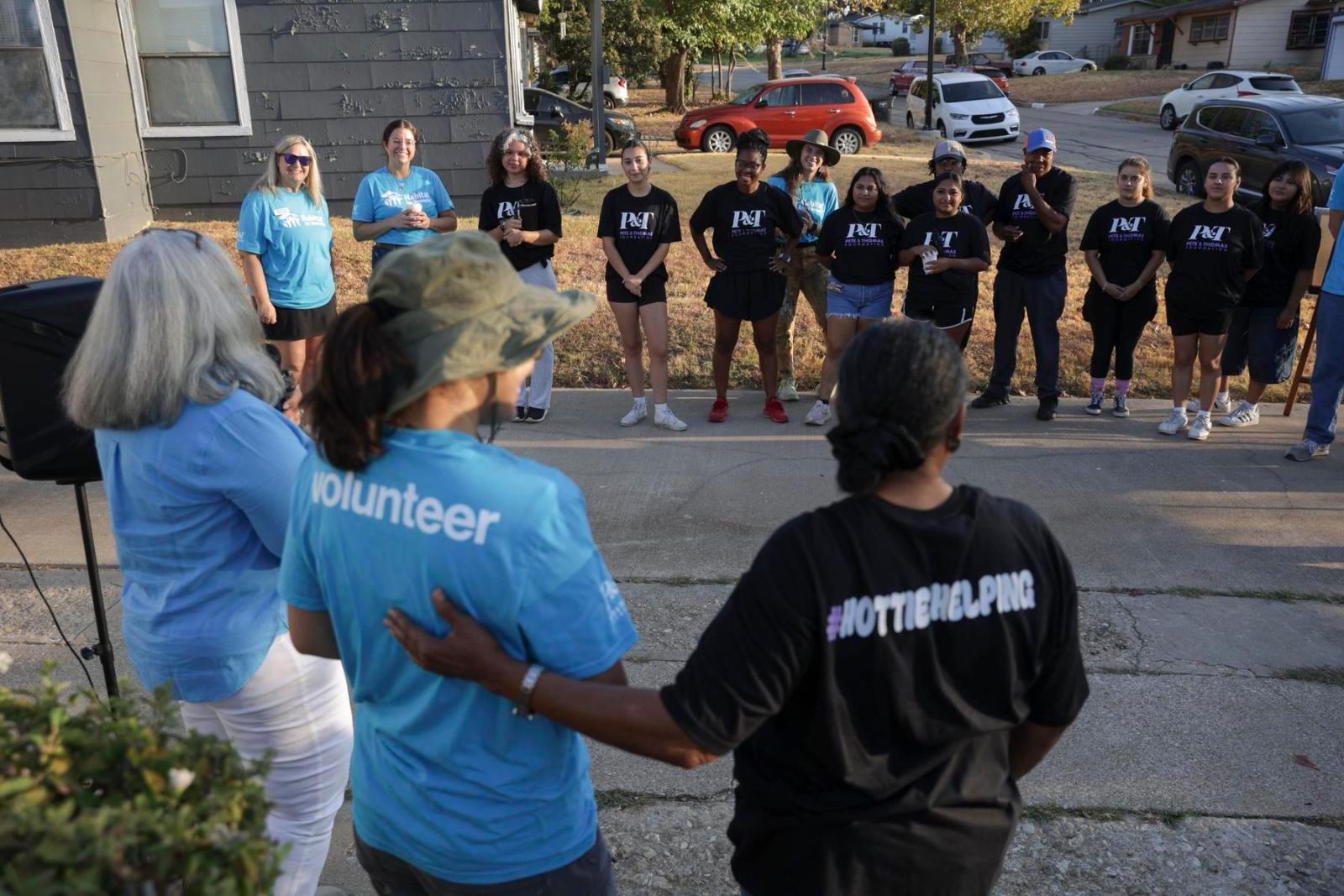 A group of volunteers, some in Habitat shirts and some in Pete and Thomas Foundation shirts, stand in a semi-circle.