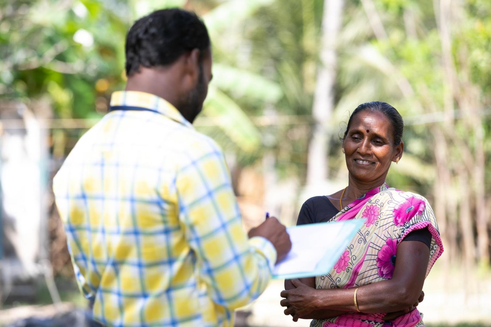 A man holds paperwork and speaks to a woman about housing finance.