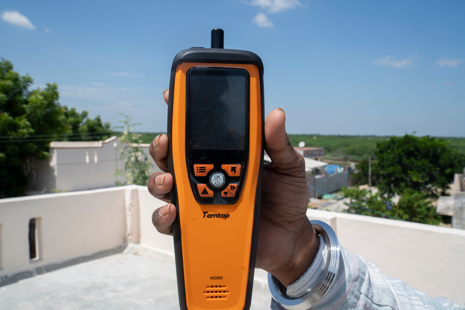 An engineer holds up an orange and black electronic tool to survey one of the cool roofs included in the study.