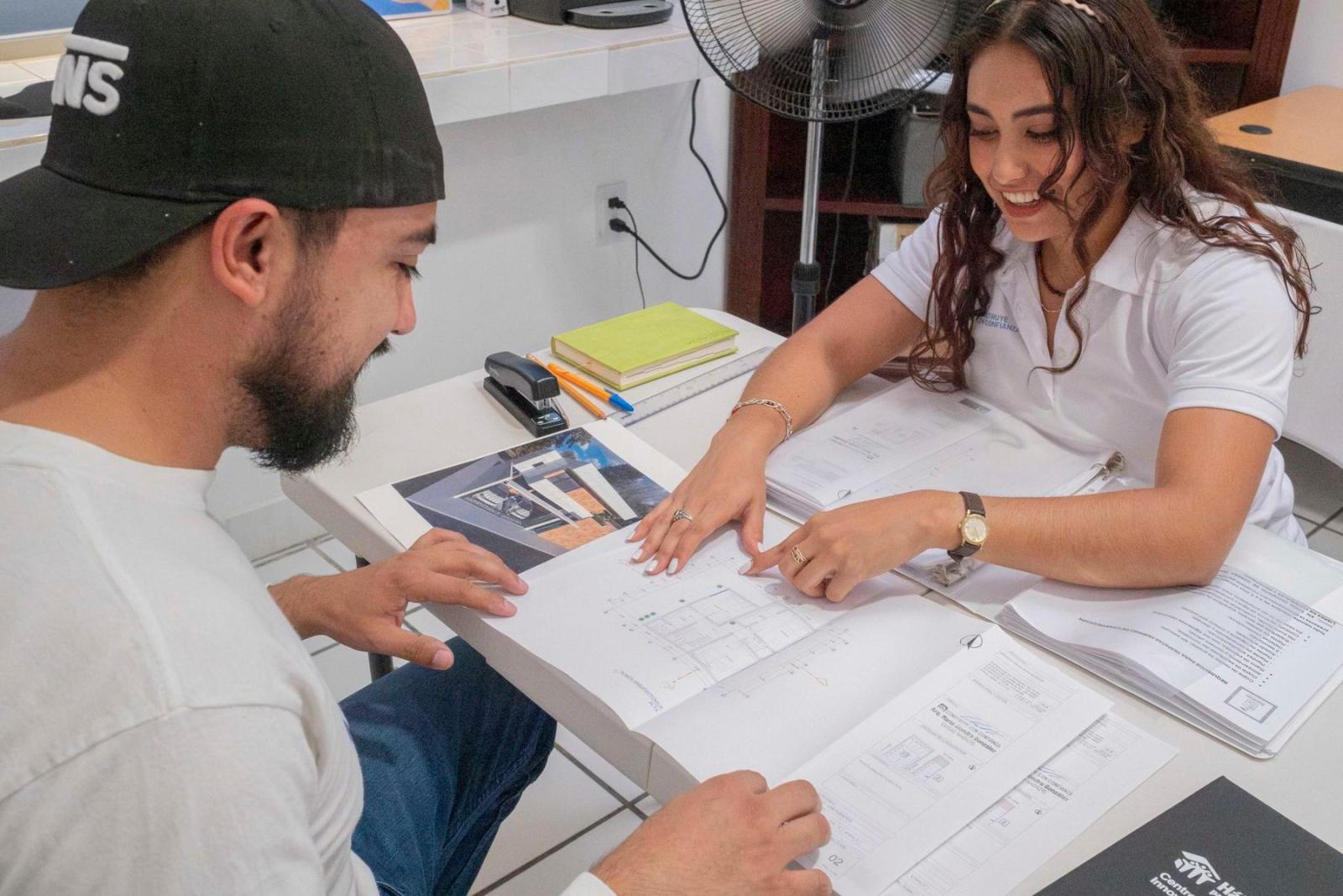 A woman shows a man layout plans for a home.