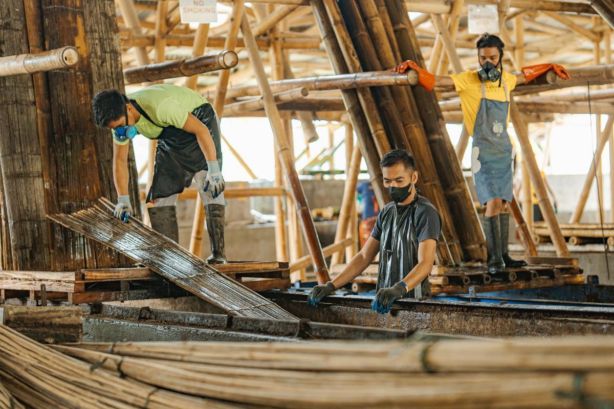 Bamboo being treated by three male workers at the Kawayan Collective warehouse in Dauin.