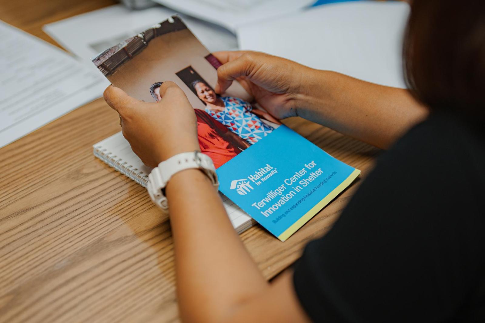 A pair of hands holds a Terwilliger Center brochure on top of a wooden desk.
