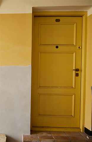 Una puerta principal de color amarillo brillante con manija negra.
