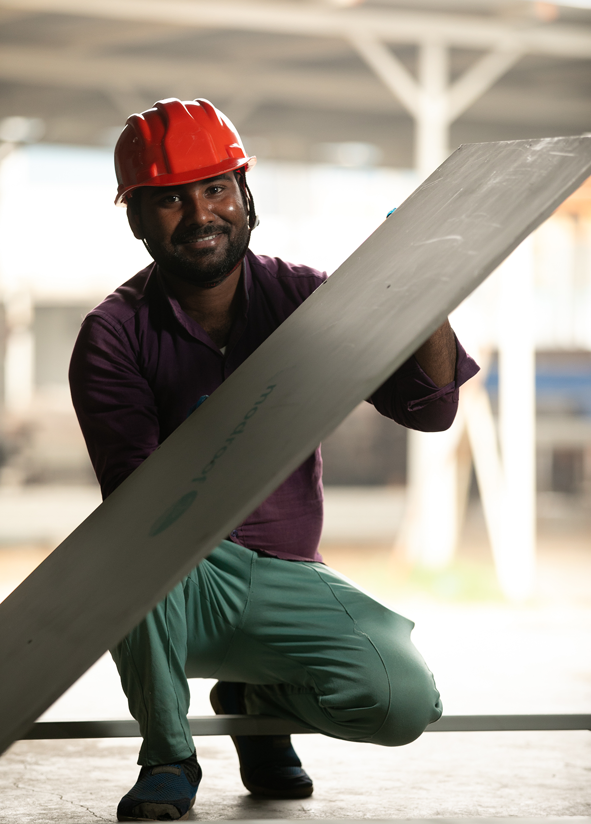 Re-materials employee Asif Ansari smiling in an orange hard hat and holding a tilted ModRoof panel in his hands.