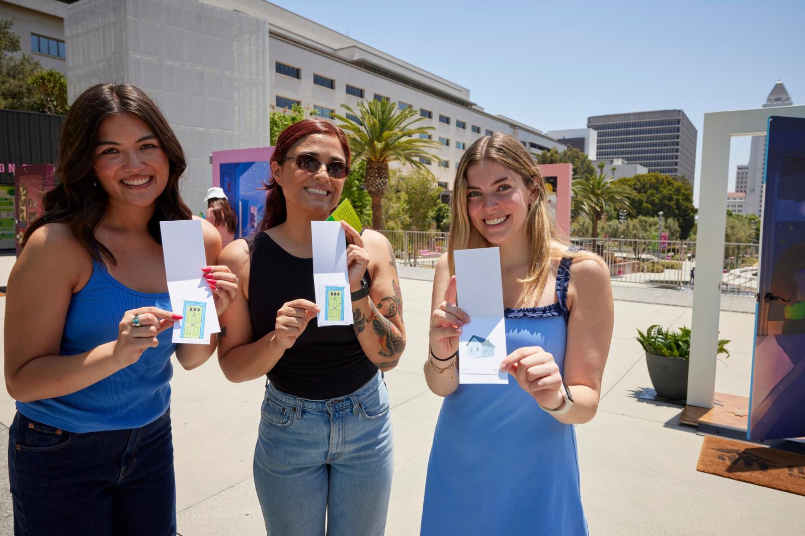 A group of three women holding up their mini prints. 
