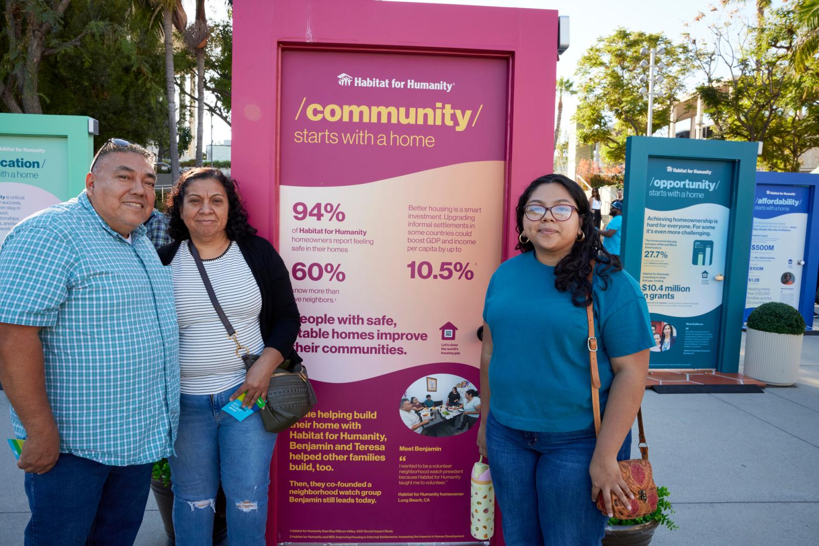A group of people posing in front of a door that displays how housing opens doors for opportunity.