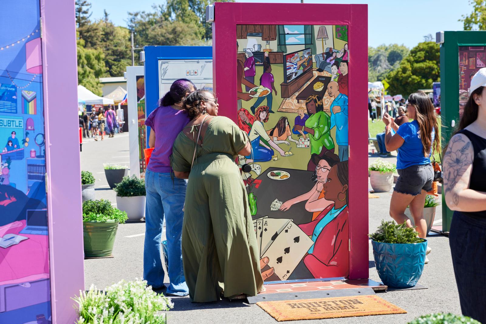 Two adult women viewing an illustrated door with a red frame.