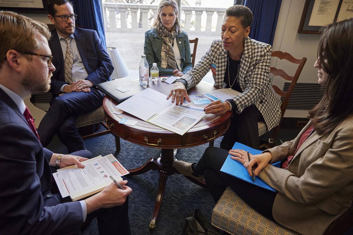Three men and three women sit around a table in an office on Capitol Hill to discuss housing solutions with their representatives.