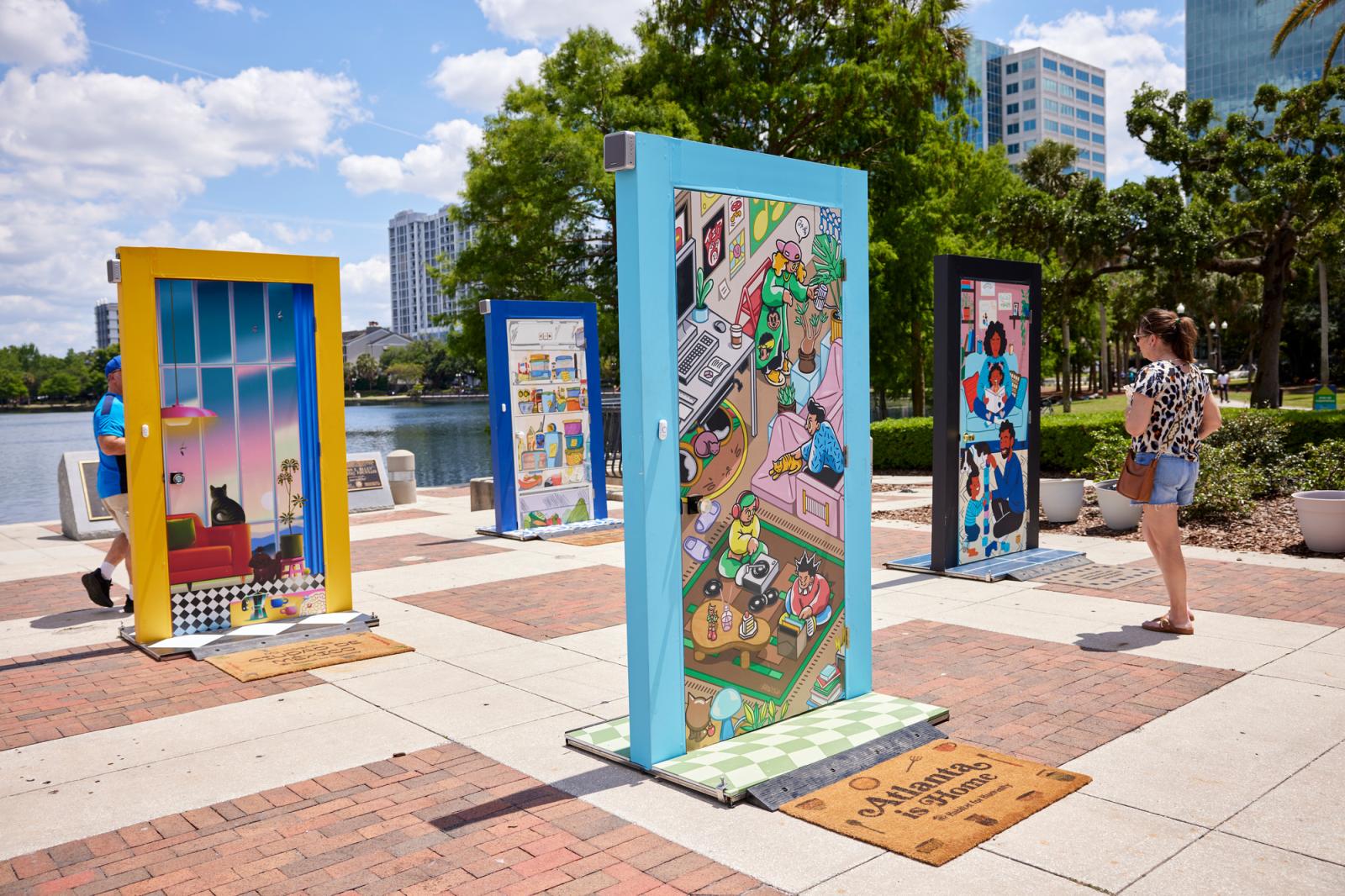 Multiple doors with yellow, blue, teal and purple door frames displayed in public.