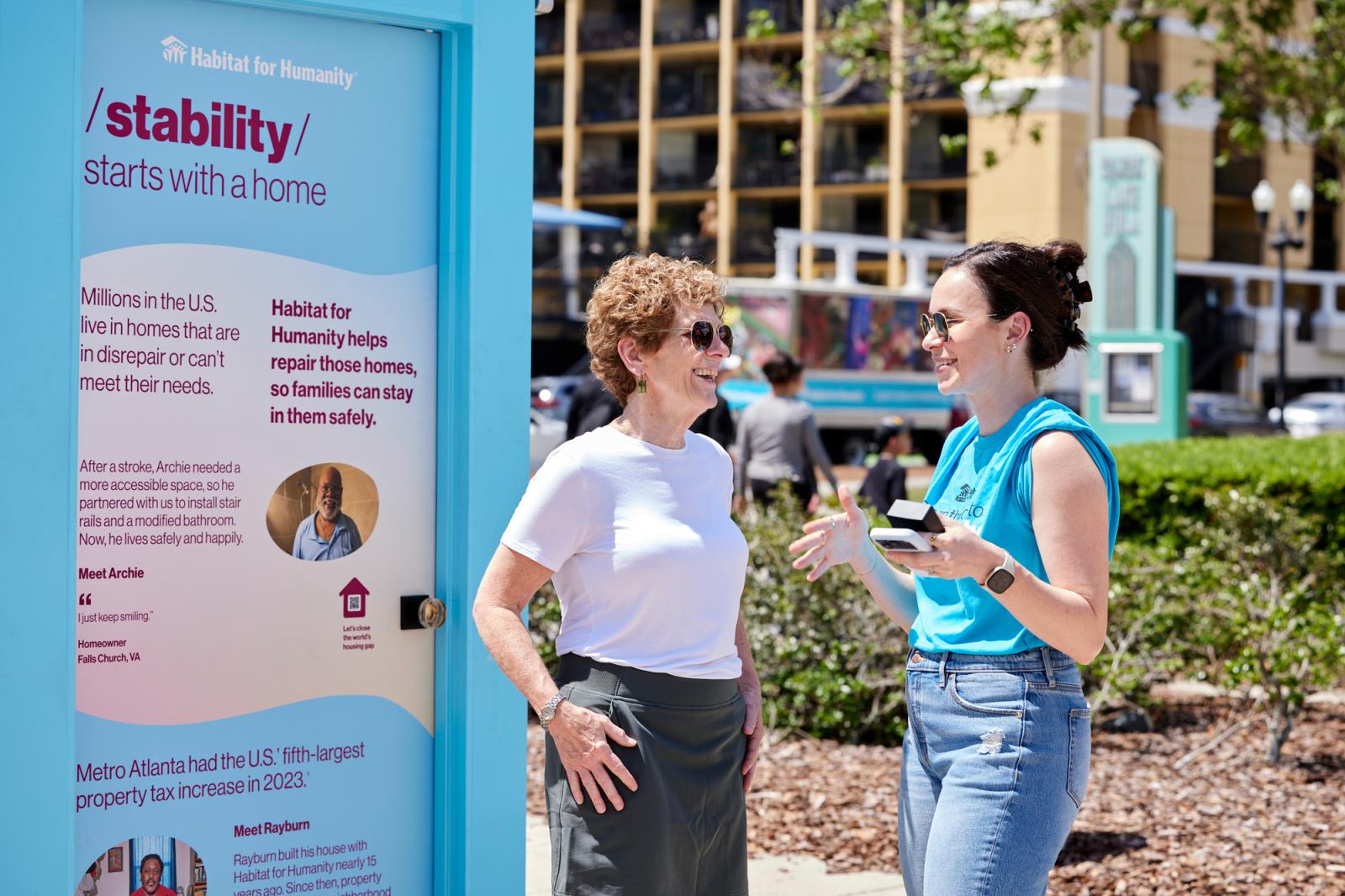 Two women standing in front of a blue door depicting the impacts of home on stability.