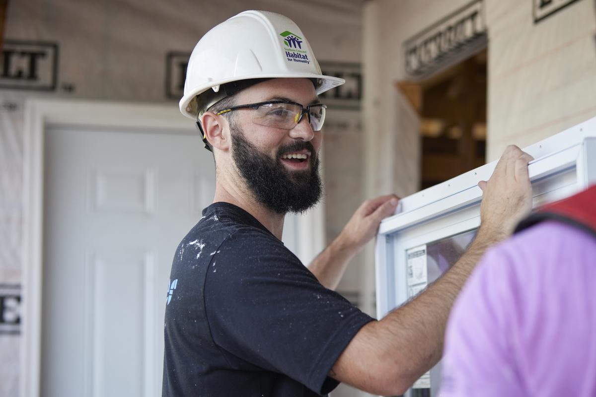 Veteran carrying a window casing on Habitat build site.