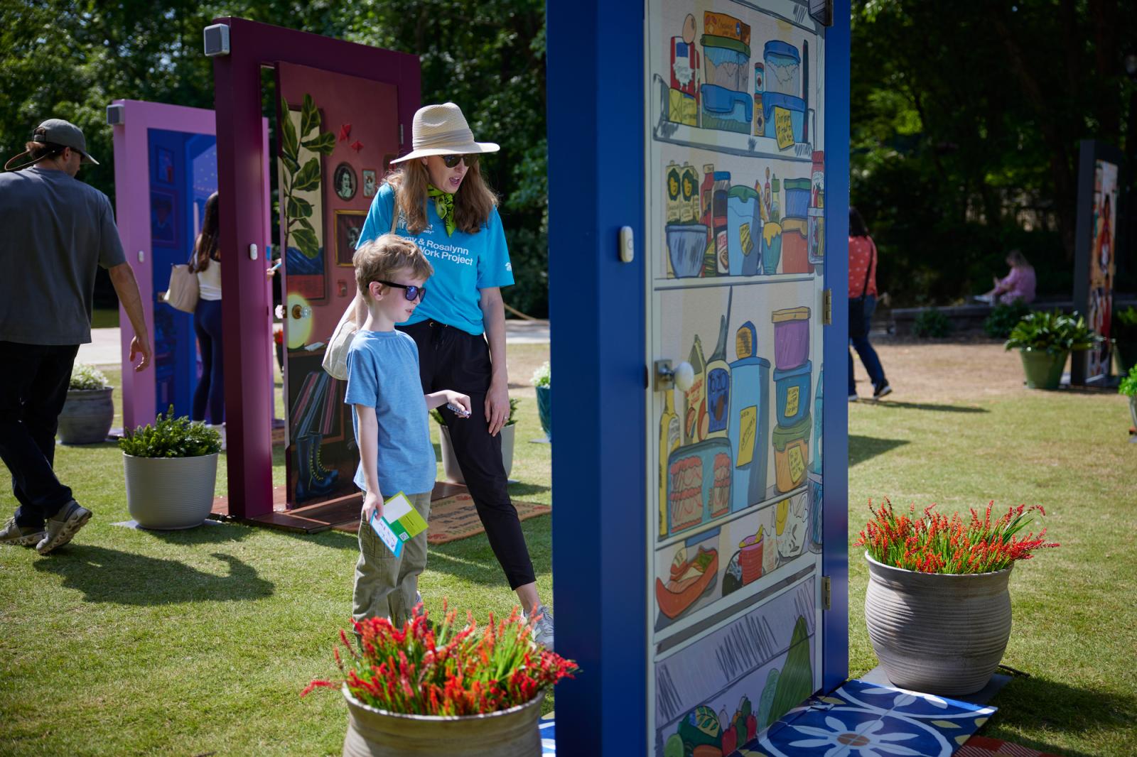 Mom and son in bright blue habitat t-shirts viewing an illustrated door with a blue frame.