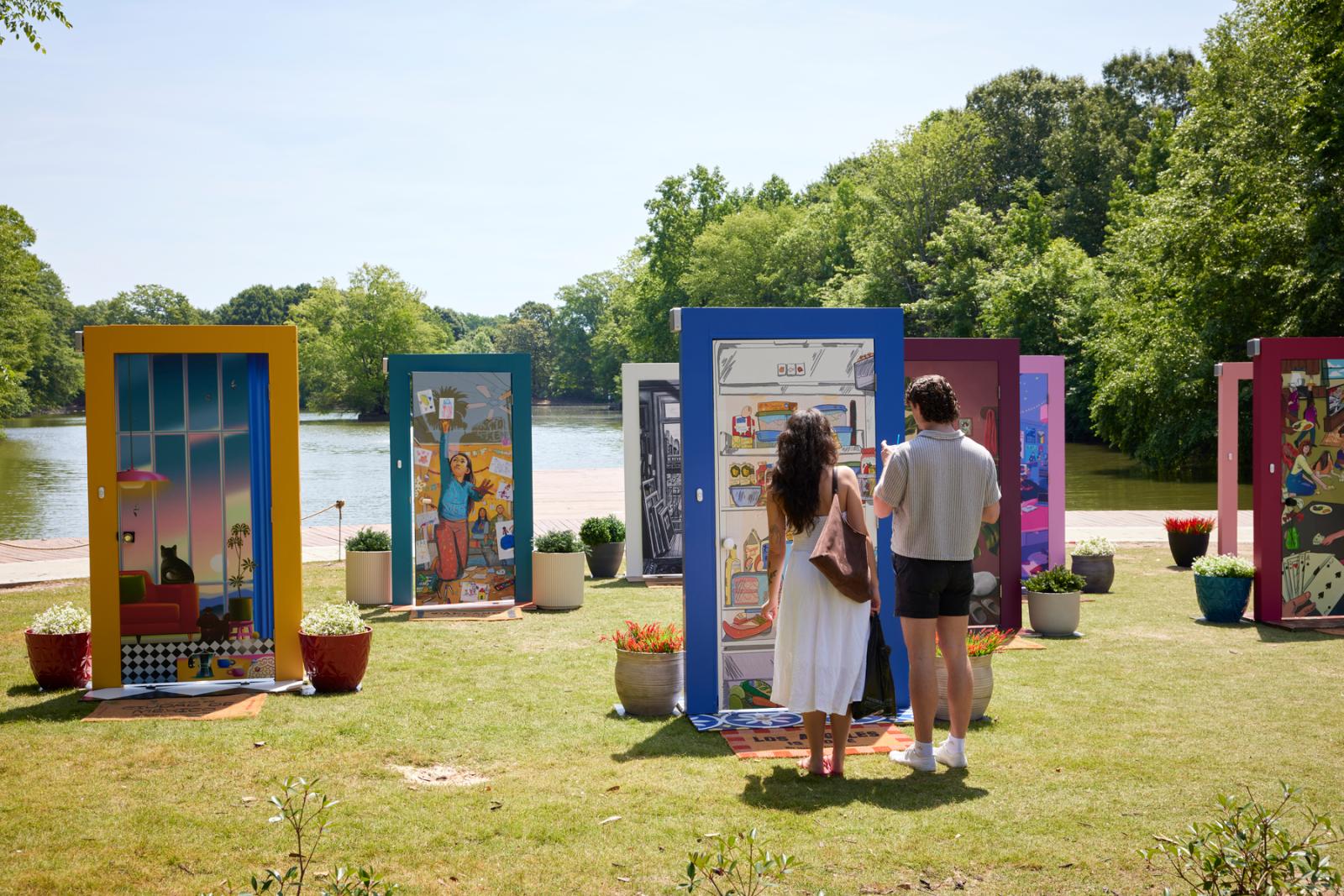 A man and a woman stand in front of a blue-framed door as part of the pop-up door exhibition.