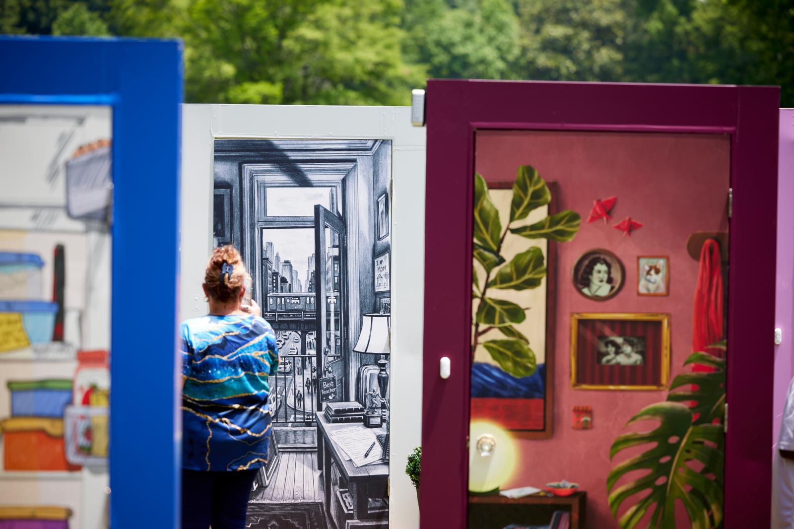 View of three illustrated doors with a woman viewing them. 