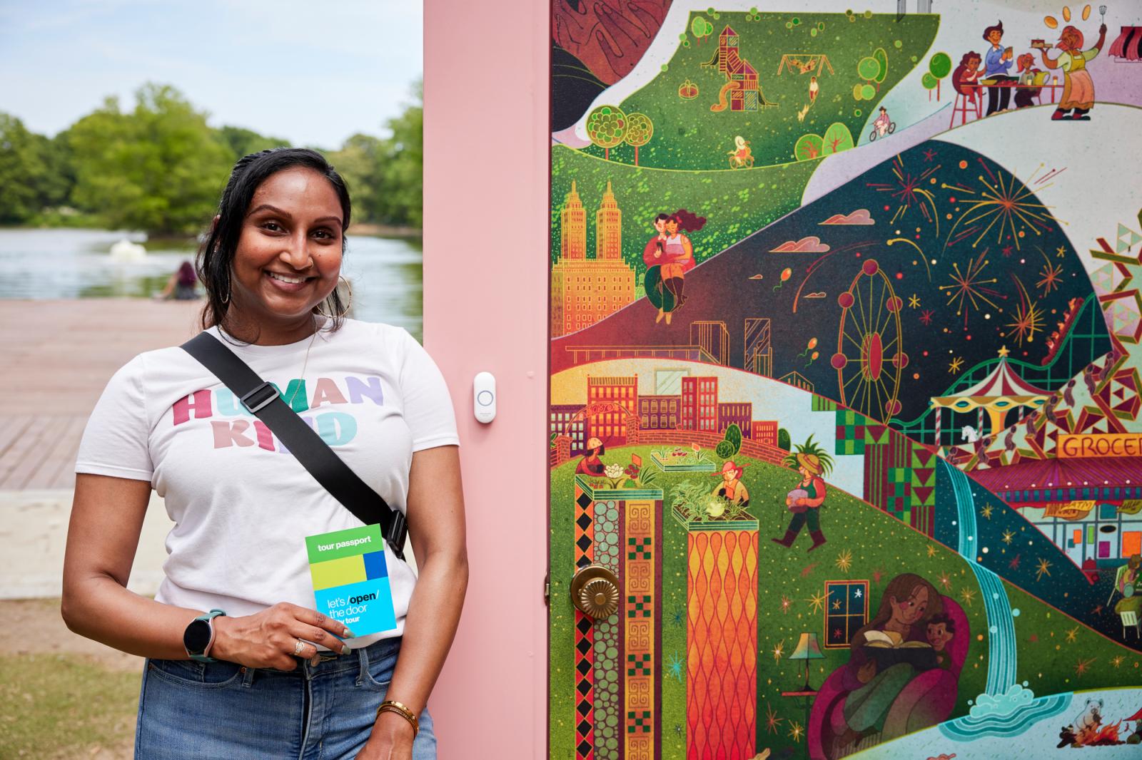 Woman in a white t-shirt and jeans with dark hair standing next to an illustrated door with a pink frame.