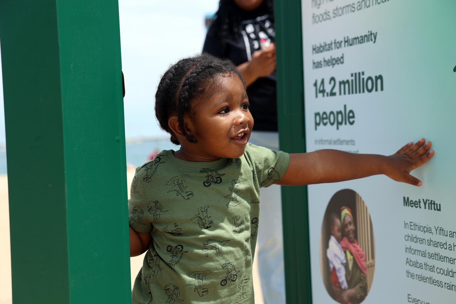 Little boy in a green shirt walking through a door with a green frame.