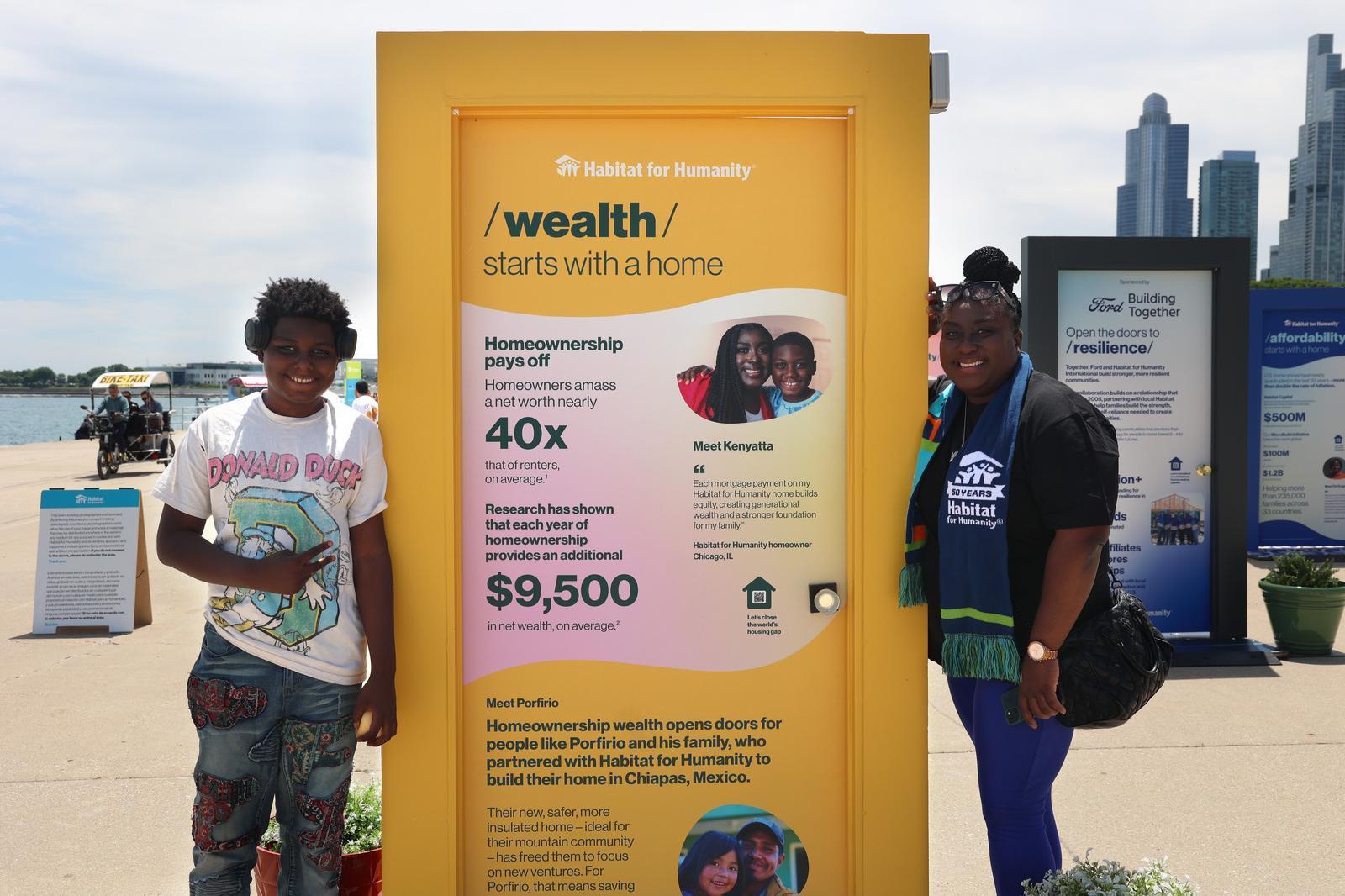 A teenager and woman in jeans and t-shirts posing on either side of a yellow door with information about how housing stability opens the door to wealth.