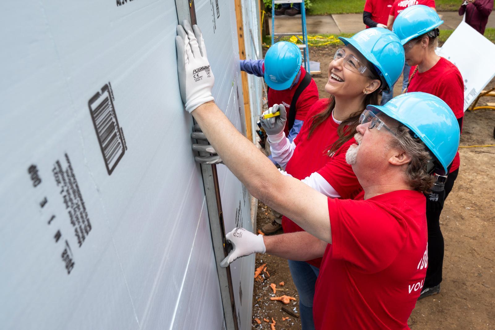 Dupont volunteers in red t-shirts and blue Habitat hard hats work on a project at a jobsite.
