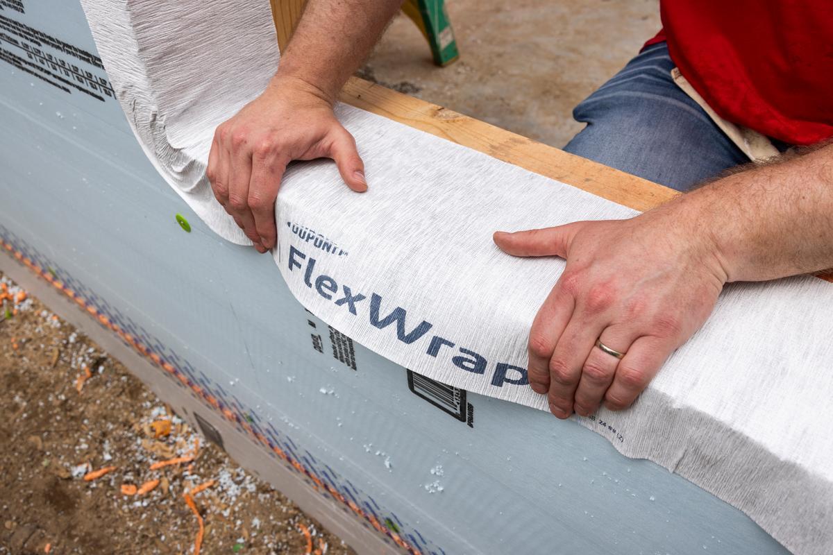 A DuPont volunteer installs DuPont FlexWrap on a Habitat house.