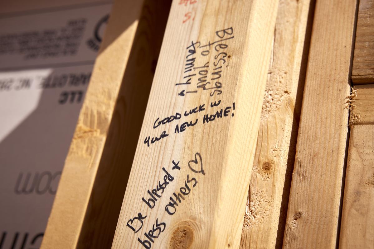 Encouraging messages written on the wooden boards of an in-progress home by volunteers.