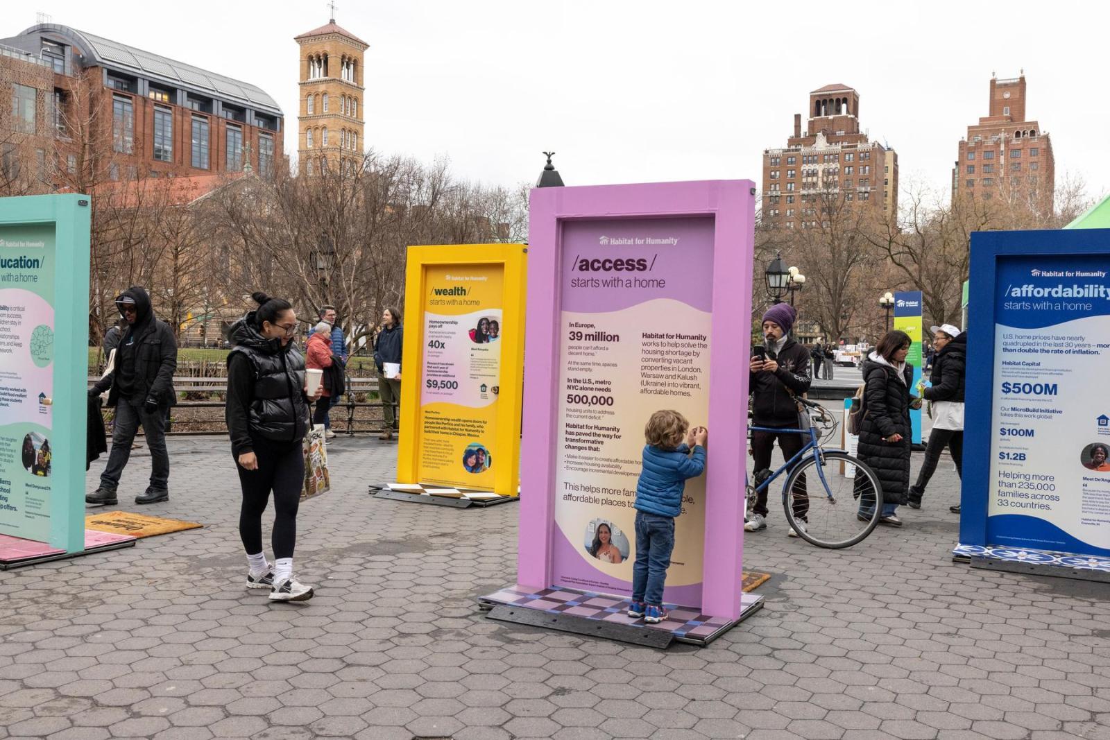 People mill around the pop-up door exhibition that is based in New York City. The doors sit on brick.