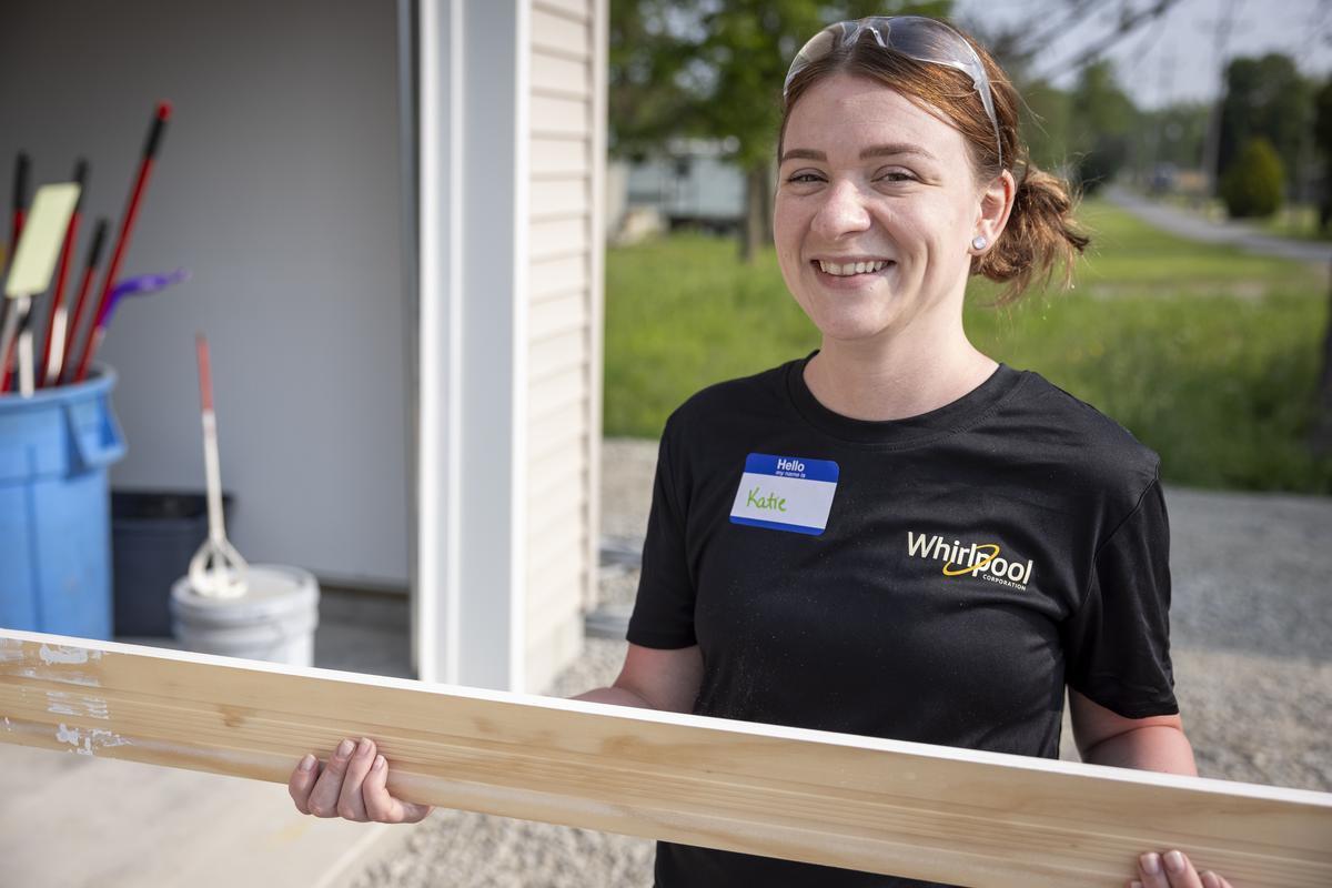 Katie, Whirlpool volunteer, helps cut floor trim. 
