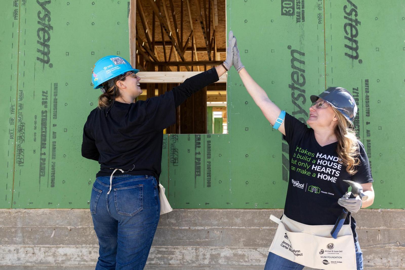Two volunteers stop their work during a build event to high five.