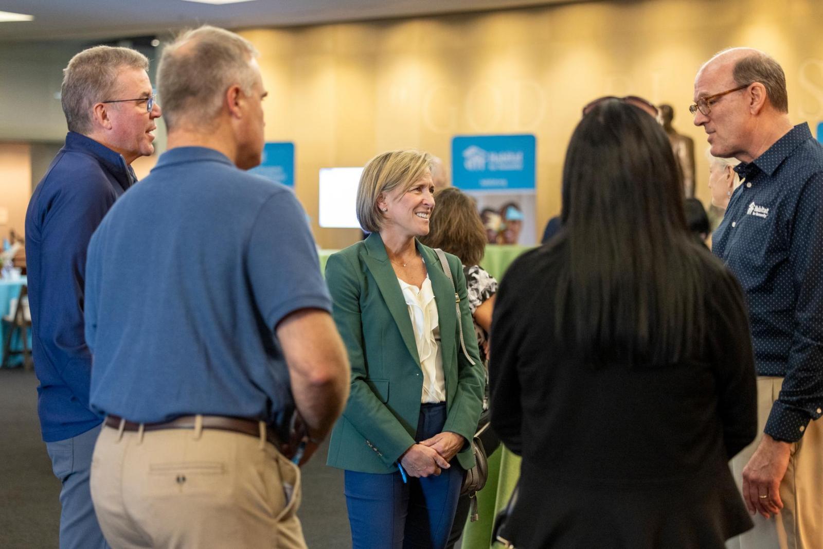 Members of the Whirlpool team stand talking to Jonathan Reckford before a build event begins.