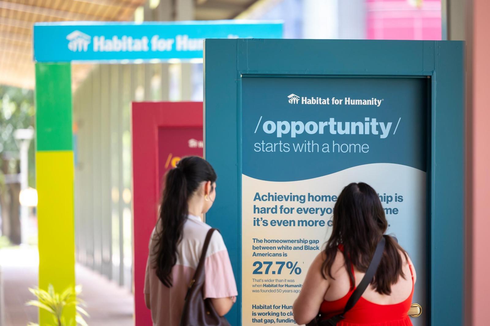Two women viewing a door that shares how housing opens the door to opportunity.