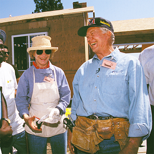 The Carters standing together on a build site, laughing together as they take a moment from building.