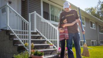 Child hugs father outside their Habitat home