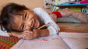 Girl smiling while doing homework.