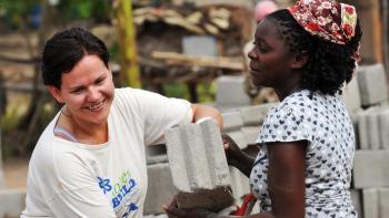 Photo: Volunteer building a wall of a house together with the future homeowner