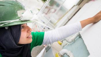 Photo: a student taking part in a volunteer program helping to build a wall