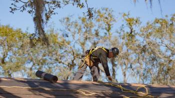 man in safety gear repairing a roof.