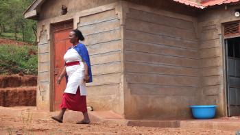 a woman walking in front of her house in Kenya