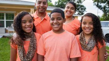 Carlos, sisters Janerys and Jarelys and parents Neryann and Javier stand in front of their Habitat home in matching shirts.