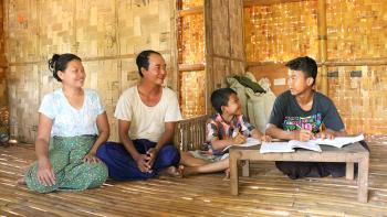 Daw Thuzar and her husband watching their sons do their homework.