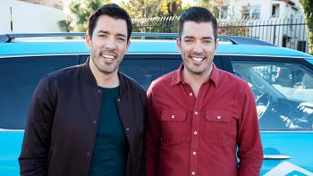 Scott Brothers smiling in front of car.