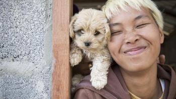 Woman smiles with puppy.