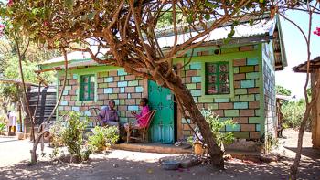colorful house in Kenya surrounded by trees build with help of micro loans