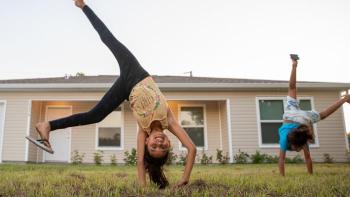 Children doing cartwheels in their yard.