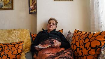 Photo: a woman from Skopje wrapped in a blanked sitting on a sofa and reading a magazine