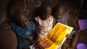 Photo: children reading a book on a sofa at home