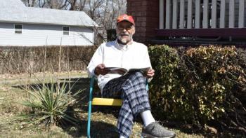 Kenneth sitting outside his home.